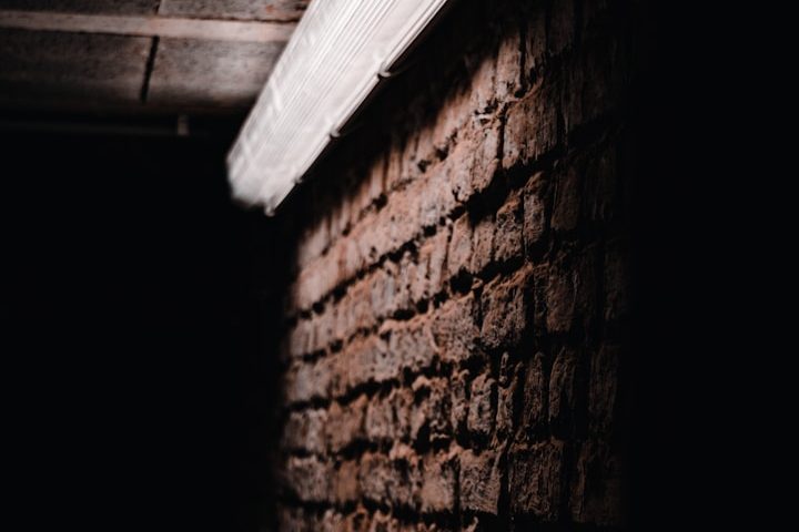 Dunkle Ziegelwand mit Lichtreflexion von einer Deckenleiste.